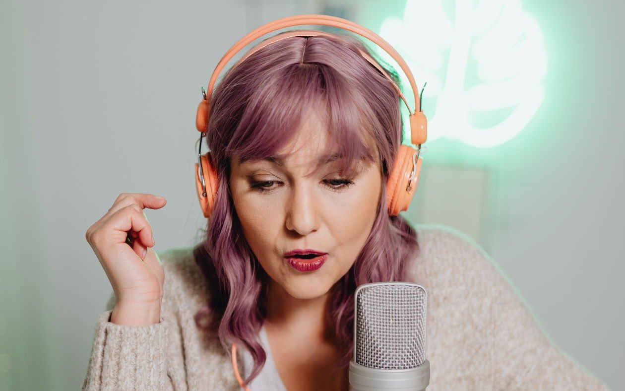 Podcaster recording an episode with headphones and a studio microphone
