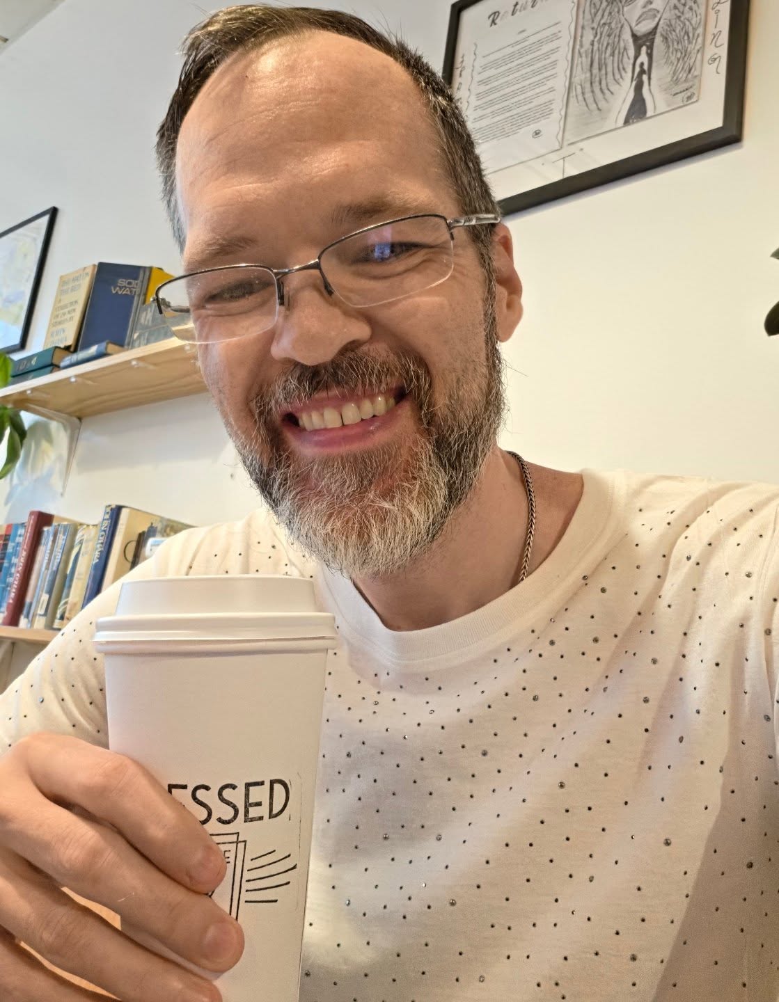 David Strausser holding a coffee at Pressed Coffee and Books
