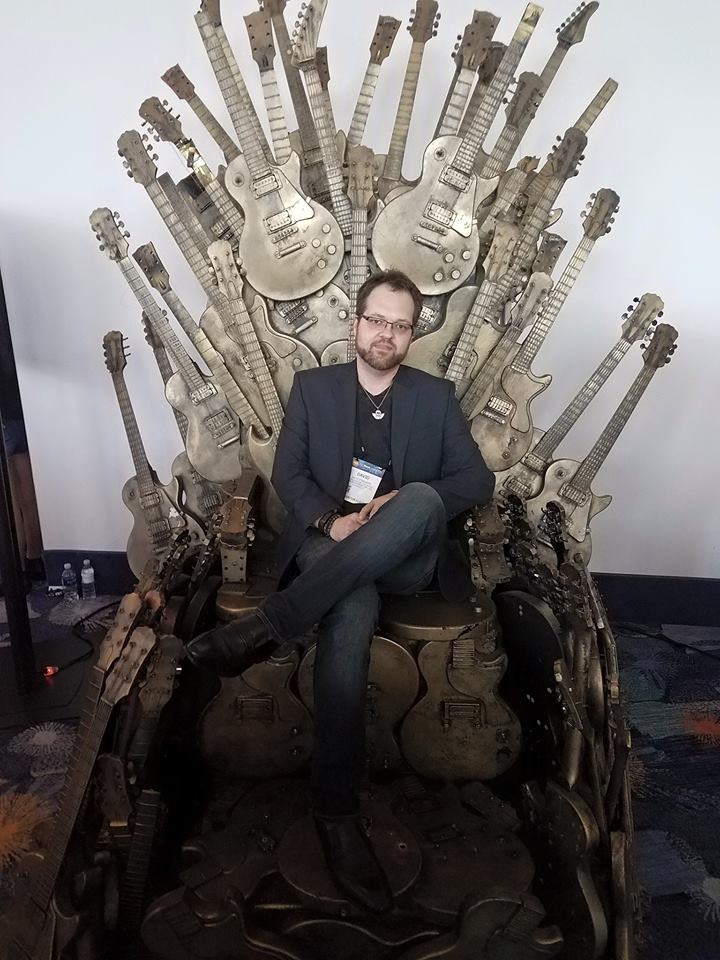 David Strausser sitting on a throne made of guitars